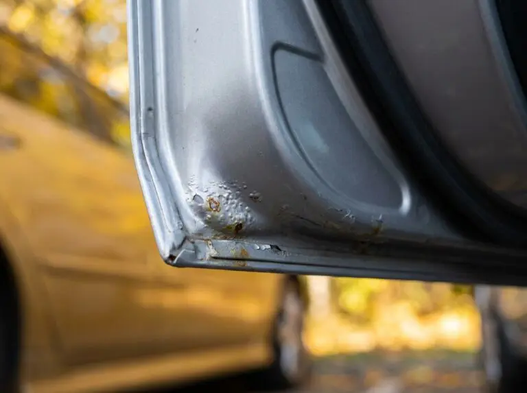 Erste Roststellen an einer beschädigten Türkante eines Fahrzeugs